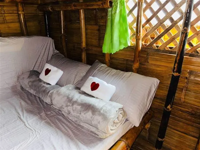 Cozy made-up bed inside a Kubo hut with folded towels